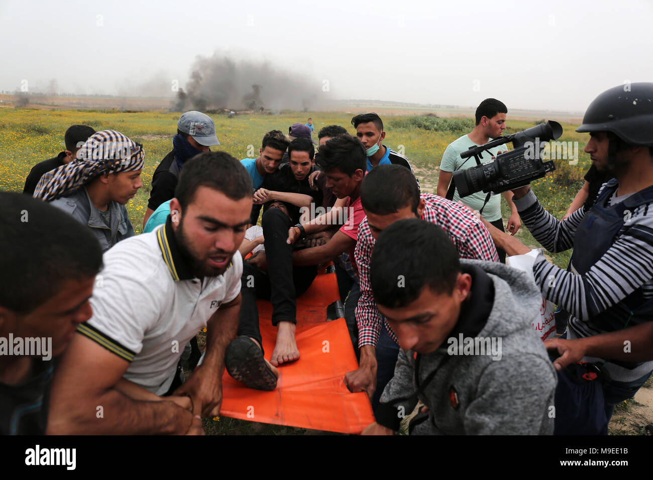 Gaza, Palestinian territories. 23rd march, 2018.   Palestinian men help evacuate an injured protester during clashes with Israeli troops near Khan Yun Stock Photo