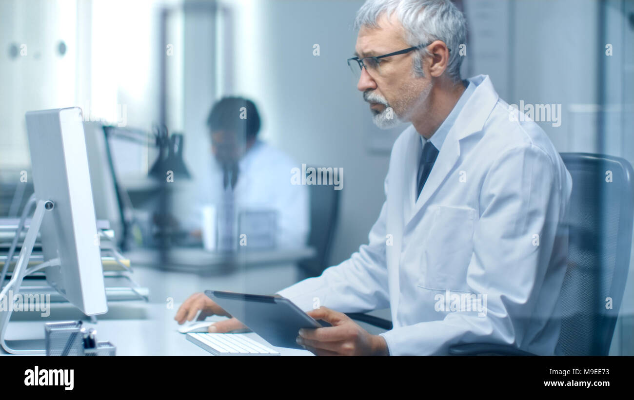 Senior Medical Practitioner Sitting Before Personal Computer Uses