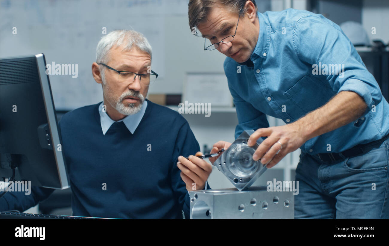 Two Senior Engineers Discuss Important Technical Components, Joining Them Together. Both are Experienced and Wise. Their Office Looks Modern Stock Photo