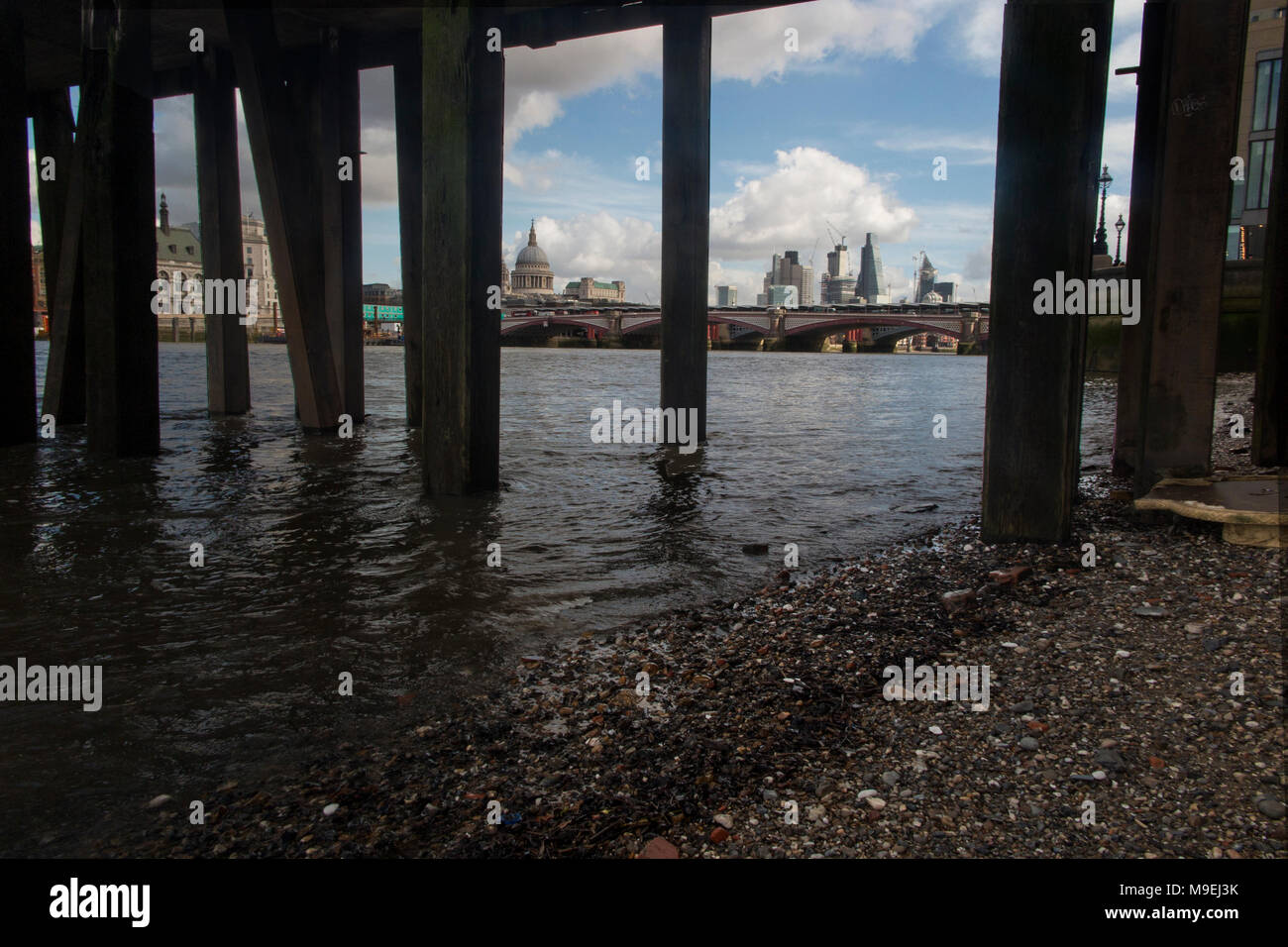 an unusual view o the City of London from underneath the wooden jetty at the Oxo Tower on London's South Bank Stock Photo