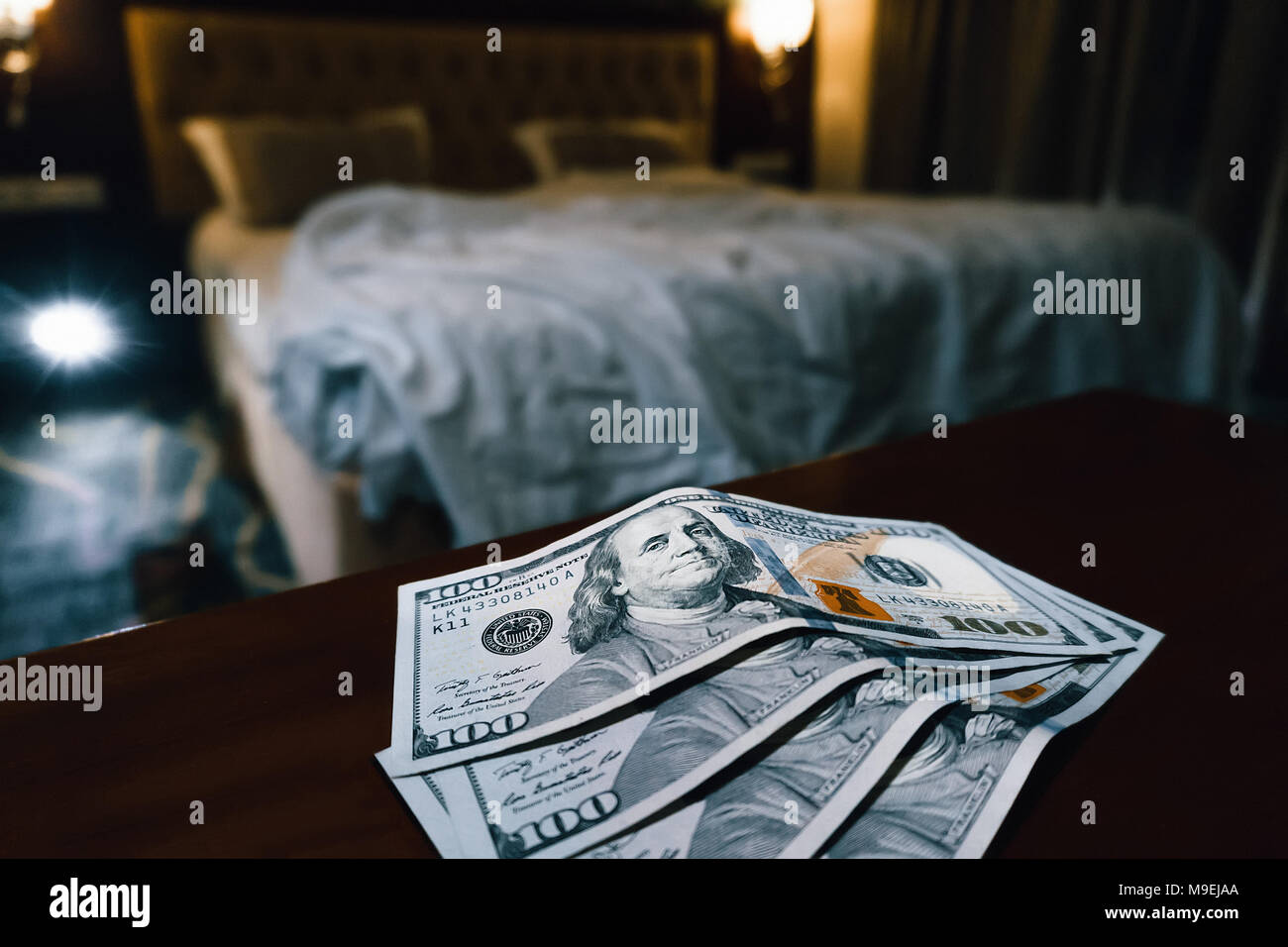 a large sum of us dollars on the table on a blurred bedroom background. selling love Stock Photo