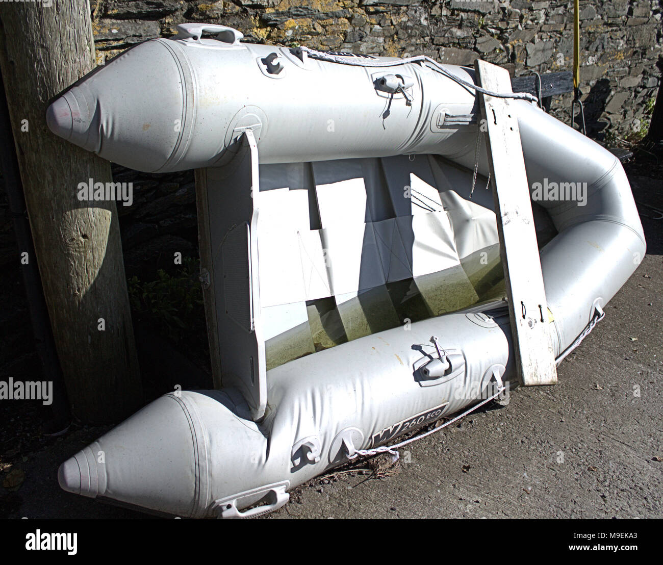 ruined inflatable dingy tied up to a telegraph pole. Stock Photo