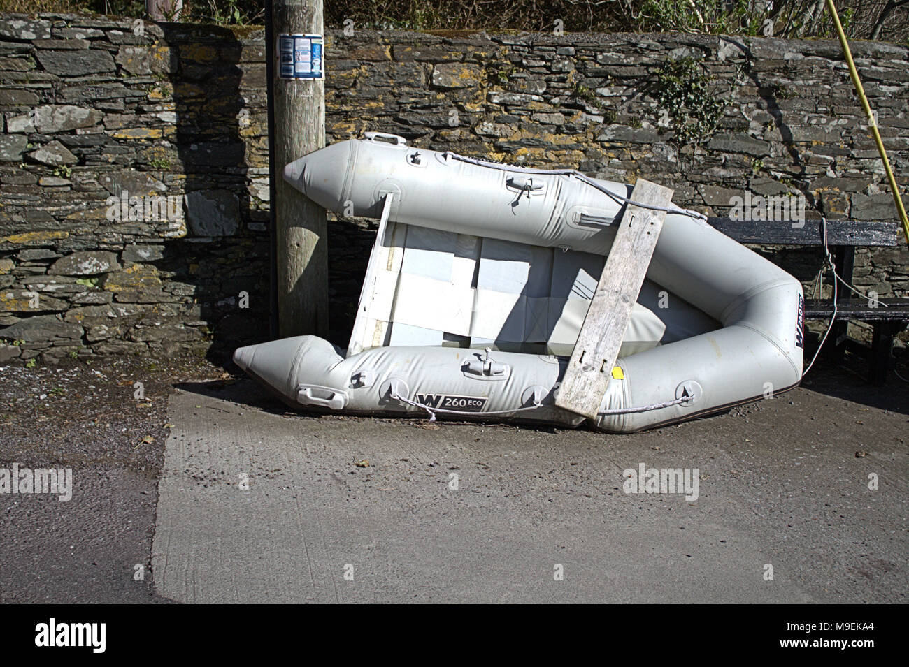 ruined inflatable dingy tied up to a telegraph pole. Stock Photo