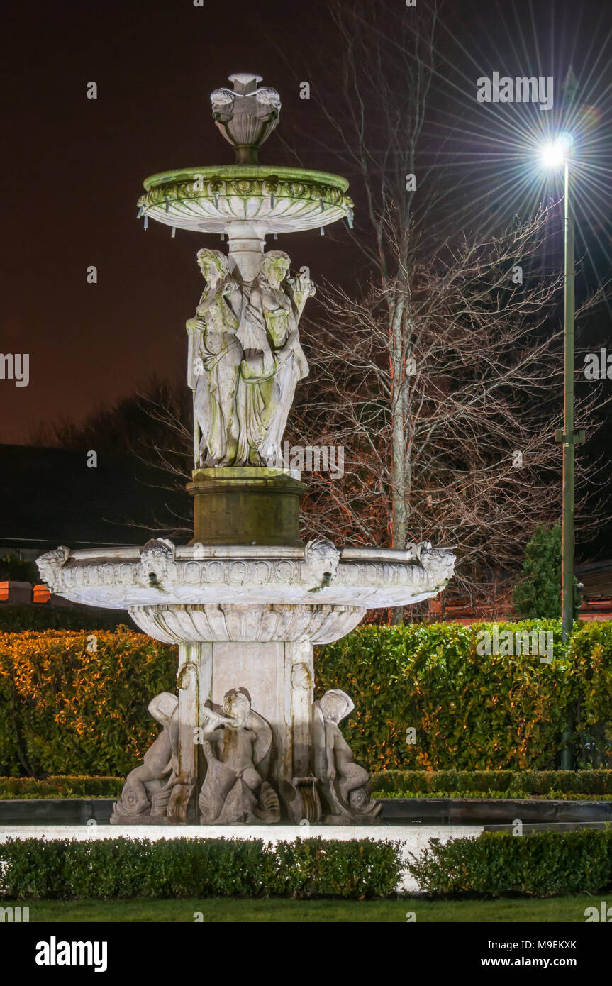 Large stone water fountain in a formal garden at night. Stock Photo