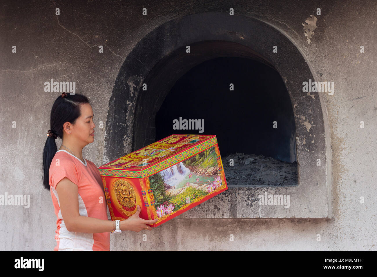 Kuala Lumpur 02 Mac 2018 - Asian woman standing at prayer burner house near a cemetery, this is a Chinese Toaish ritual offering spirit money to the a Stock Photo
