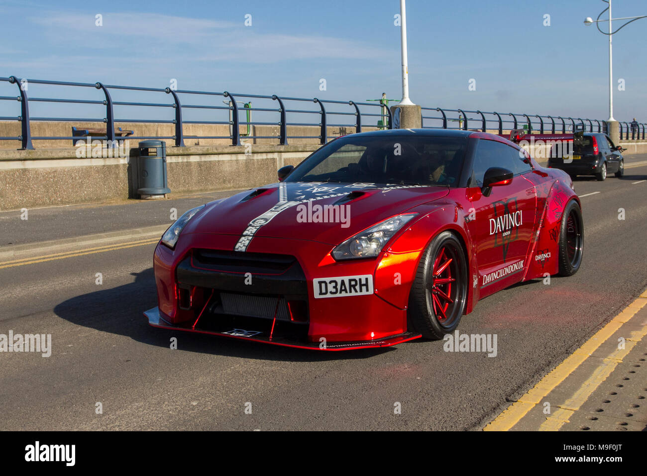 Red Nissan GT-R Davinci sports car at the North-West Supercar event as cars arrive in the coastal resort of Southport. SuperCars are bumper to bumper on the seafront esplanade as modern classics, sports cars & Canon Run car enthusiasts enjoy a motoring day out. Stock Photo
