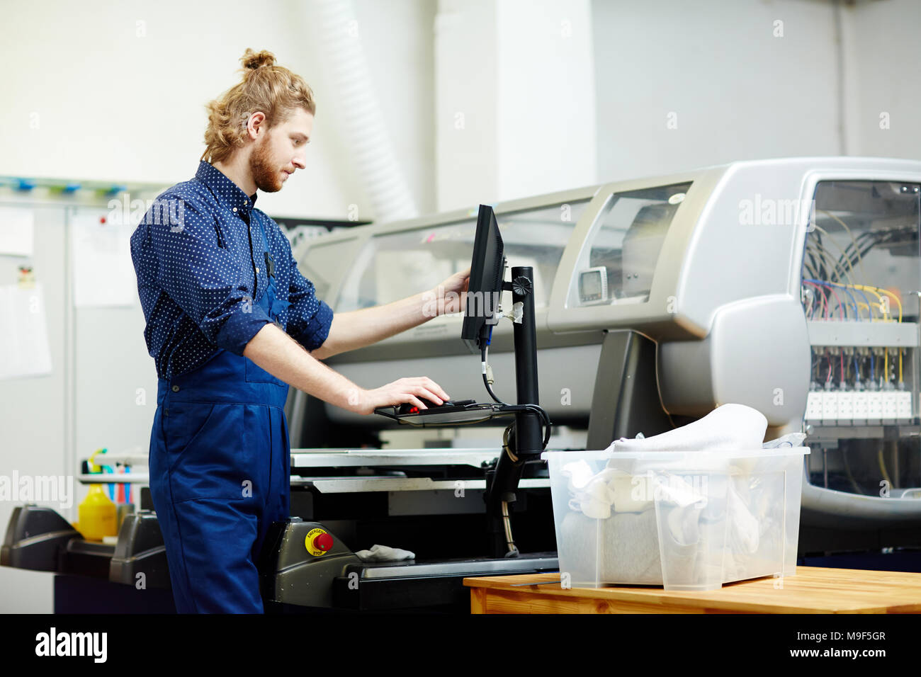 Typographer working with printing machine on factory Stock Photo