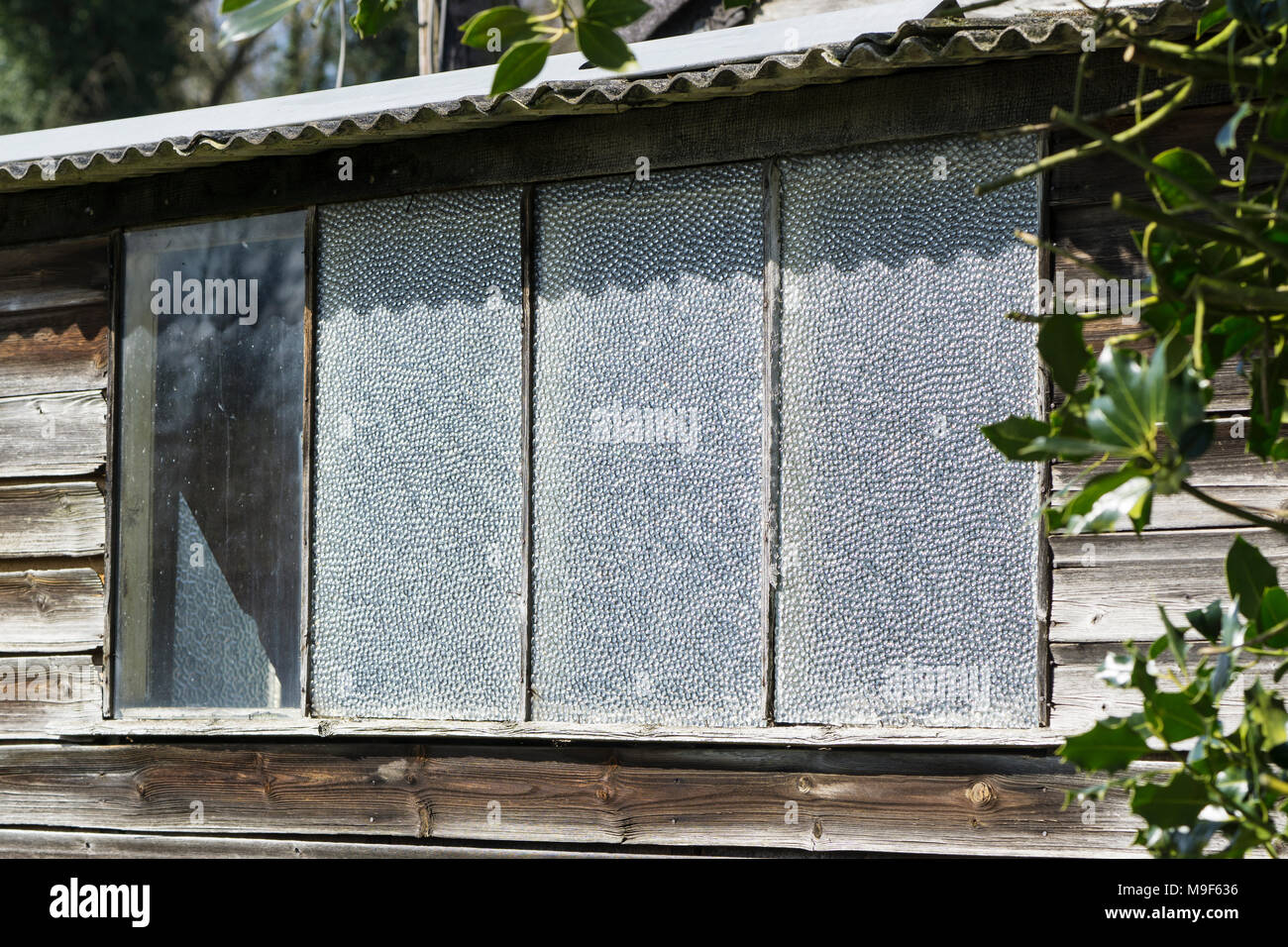 Three peppled glass panes in shed window Stock Photo