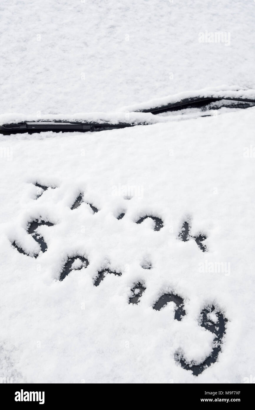 The message 'think spring' written in fresh snow on a car bonnet after an early season snowfall. Stock Photo