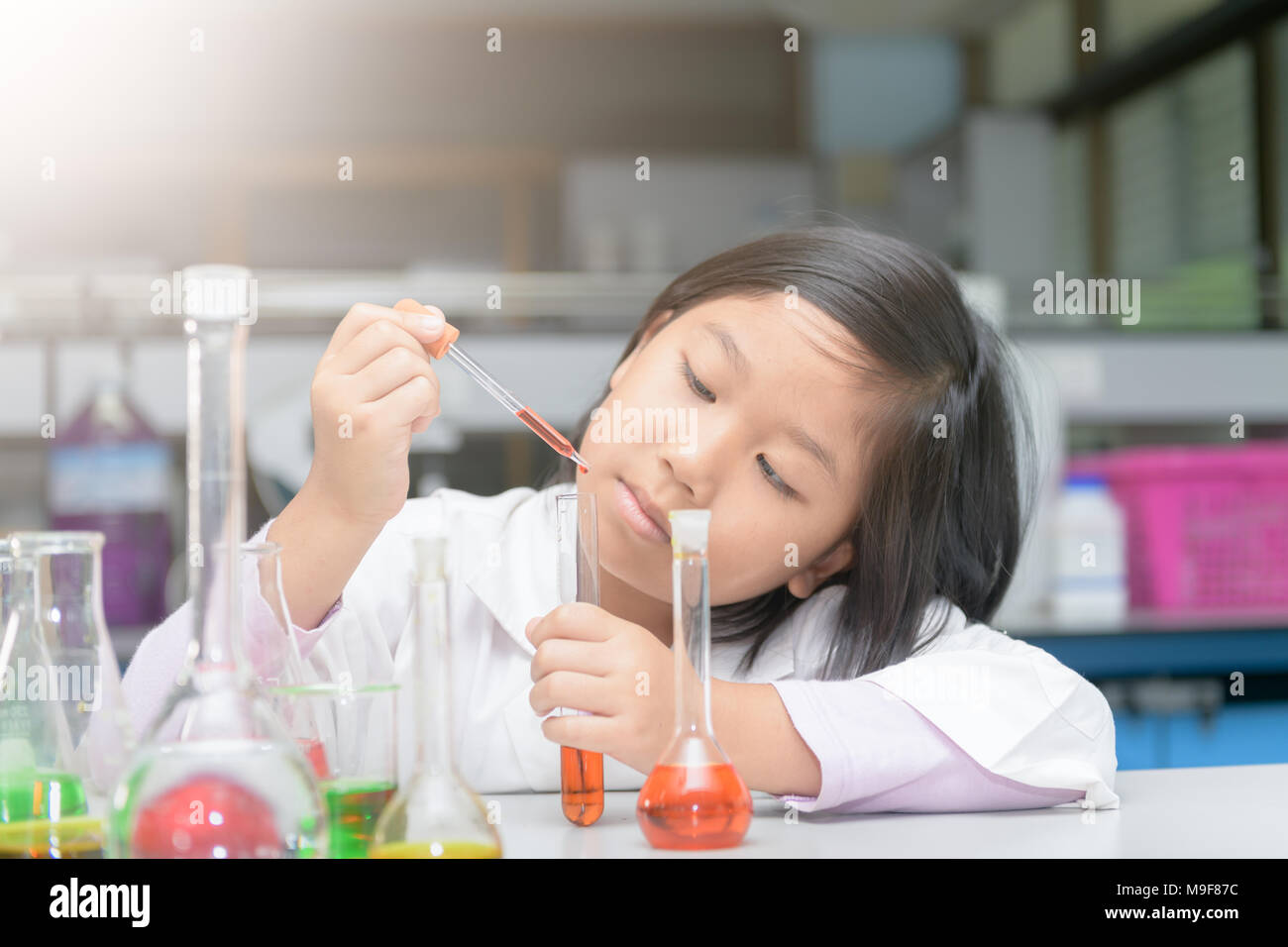 little girl in lab coat making experiment with test tube in chemical