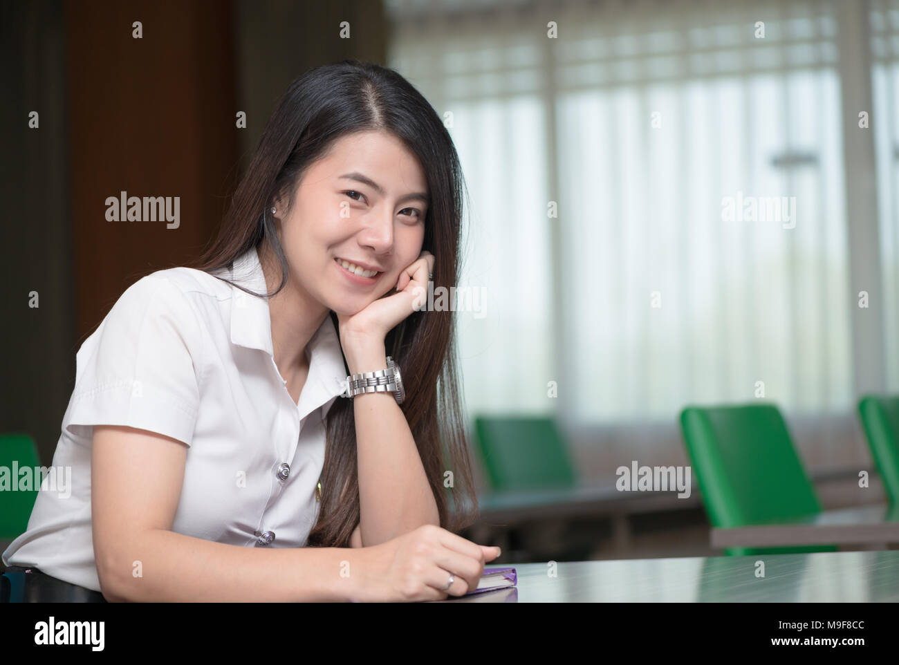 cute young asian student in uniform smile and sit in classroom, education and learning concept Stock Photo