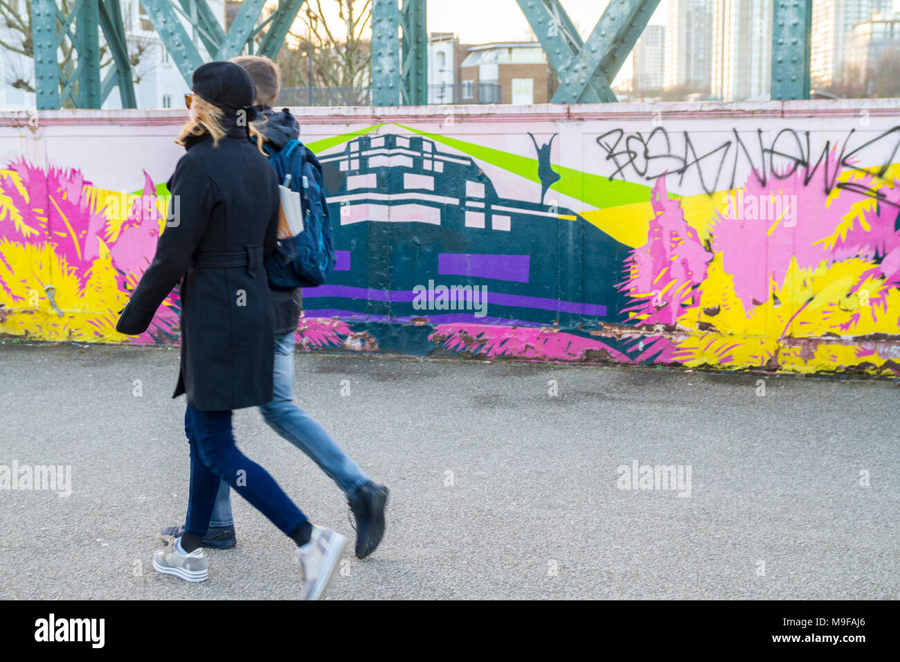 People walking by, Pedestrians walk past, street art, graffiti on a bridge in Primrose Hill, London UK everyday life living couple walking youth young Stock Photo