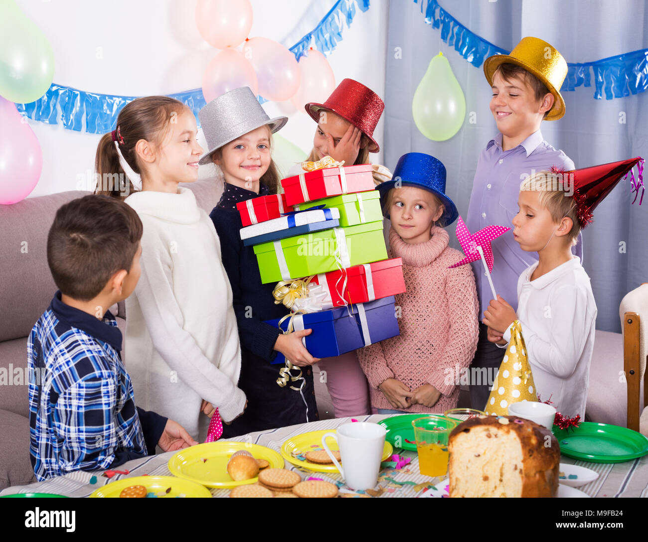 Boys and girls handing presents to birthday girl during party Stock ...