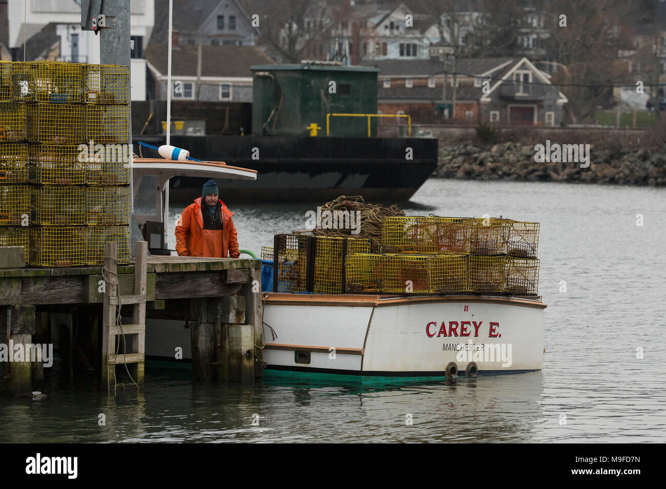 A fisherman with his lobster traps aboard his boat in the harbor at Manchester-by-the-Sea, Massachusetts, on a winter day Stock Photo