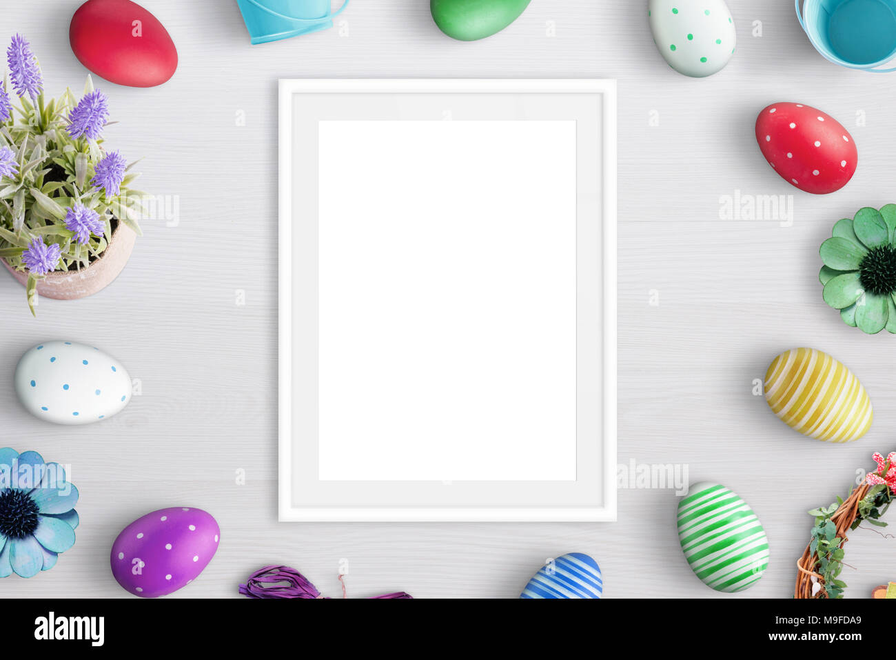 Blank picture frame surrounded with easter eggs and flowers. Stock Photo