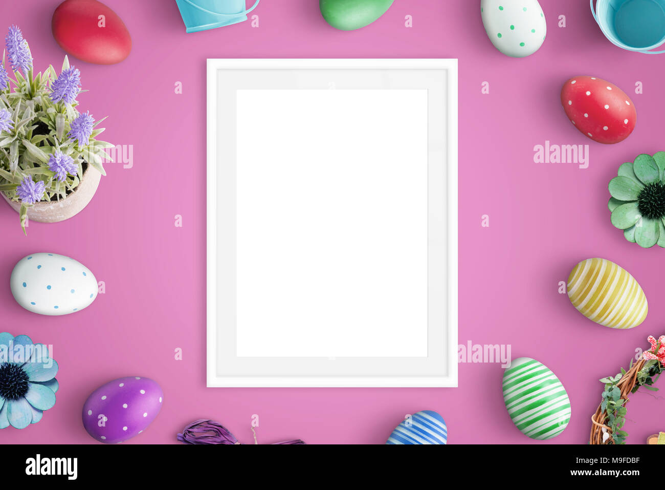 Picure frame mockup on pink desk. Easter decorations beside. Flat lay. Stock Photo
