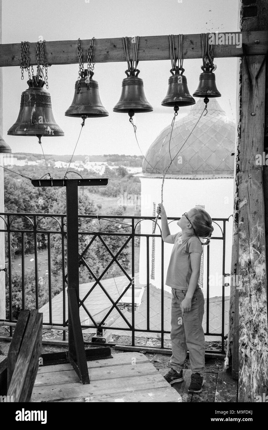 Girl rings bells in the bell tower of the old Russian Orthodox Church Stock Photo