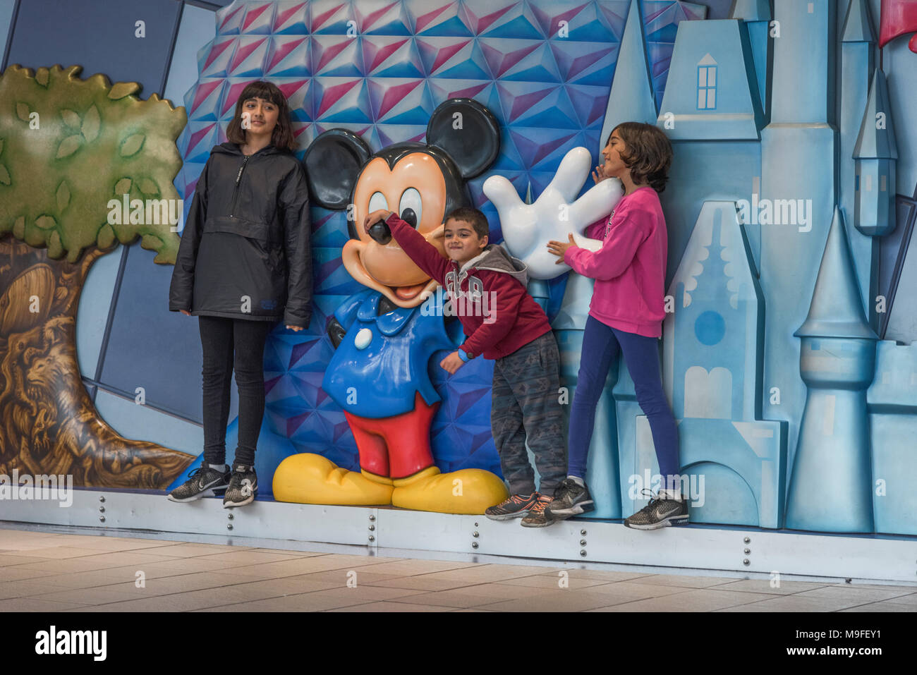 Children posing with a Micky Mouse statue located within the terminal at Orlando International Airport Florida USA. Stock Photo