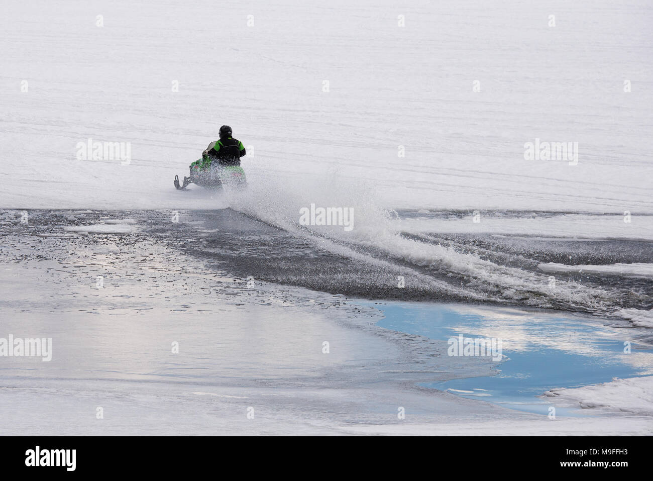 Snowmobile racing across an open patch of water on Lake Pleasant, NY in