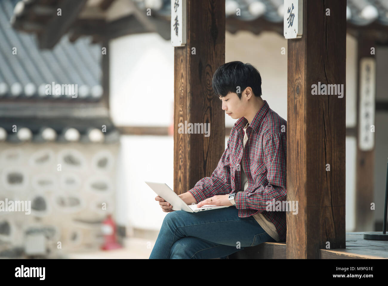Young man traveling in South Korea. using a laptop sitting in a Korean ...