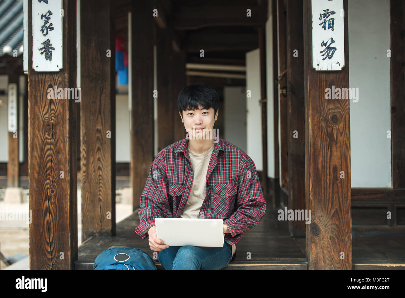 Young man traveling in South Korea. using a laptop sitting in a Korean ...