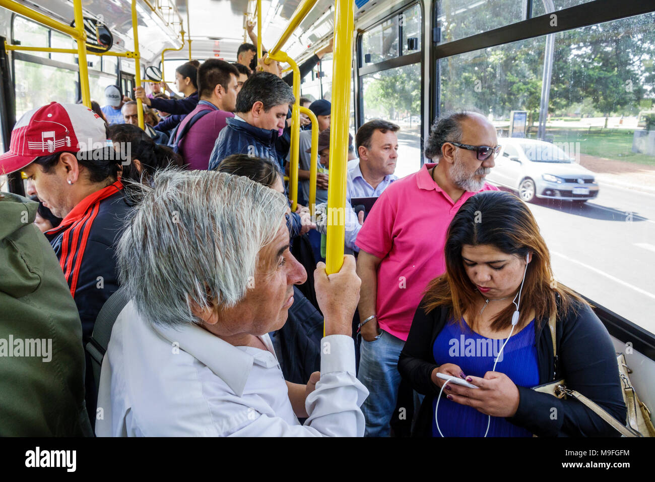 Buenos Aires Argentina,bus,passenger passengers rider riders,standing,man men male,woman female women,standing,listening,earbuds,Hispanic,ARG171128221 Stock Photo