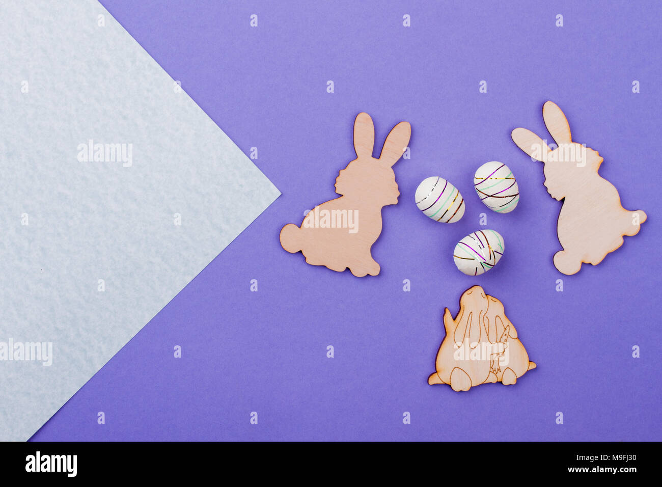 Easter rabbits from plywood. Easter bunnies wooden cutouts and styrofoam eggs on purple