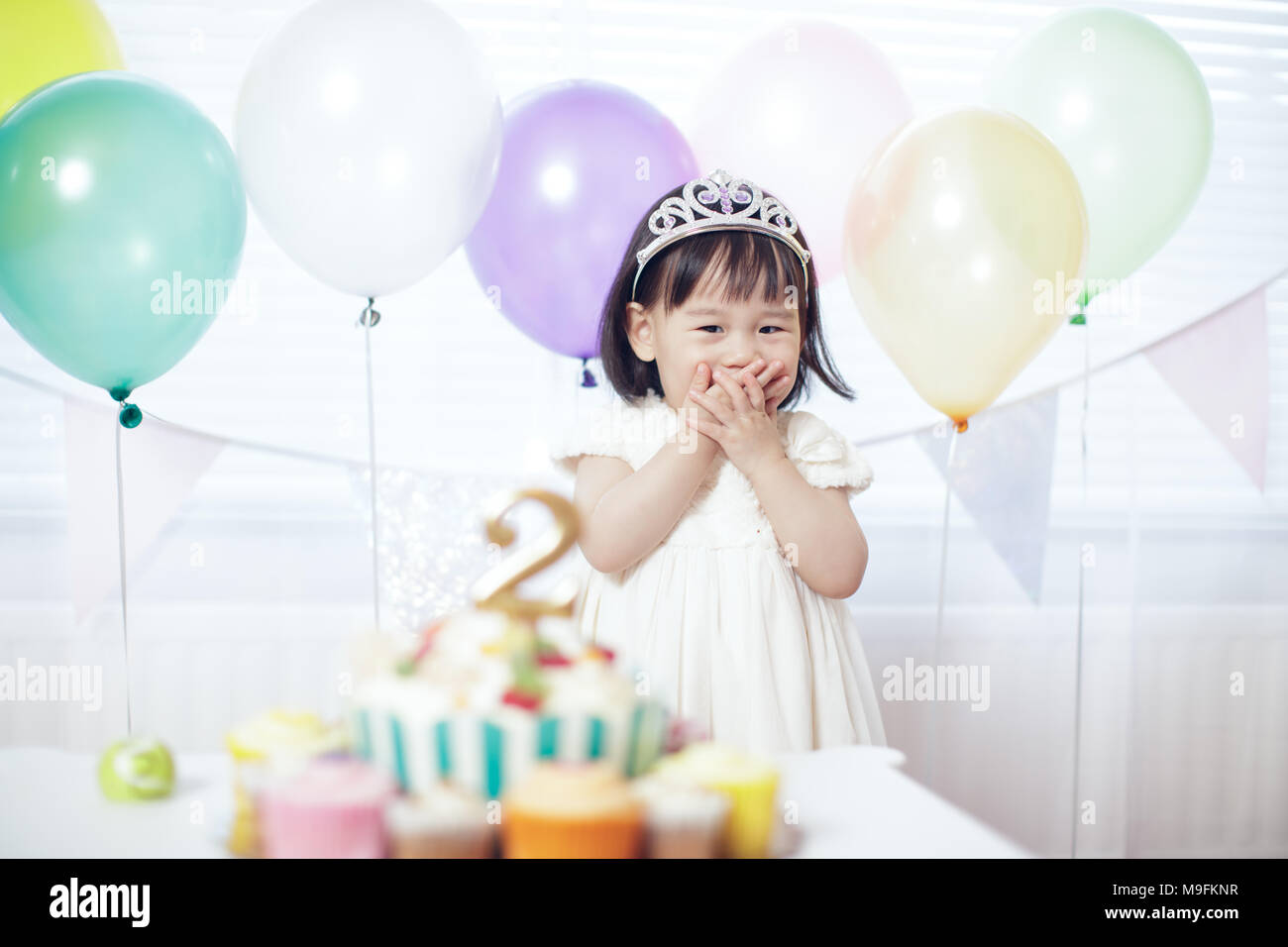 Little ginger girl wears party hat and white tshirt, stands near festive  table with cake, blows candles and makes wish during her birthday, poses in  white room with inflated balloons, smiles joyfully 7909388 Stock Photo at  Vecteezy