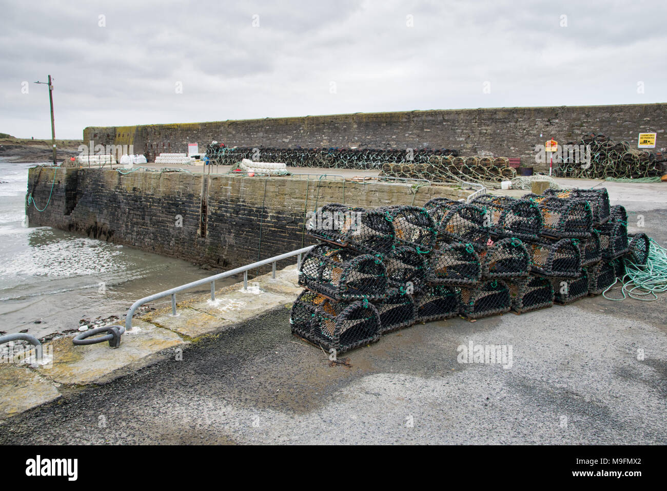Lobster post stacked up along a pier in an small Irish fishing harbour