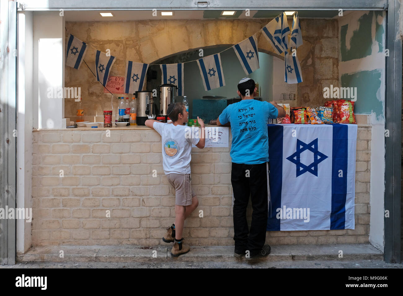 Young religious Jews buy food at a kiosk operated by Jewish settlers  in Al Wad street which Israelis call Haggai in the Muslim Quarter, old city of Jerusalem Israel Stock Photo