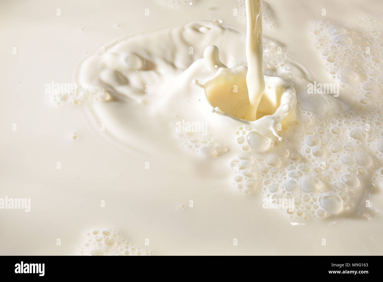 Detail of the filling of a milk container causing splashes and foam. Horizontal composition Stock Photo