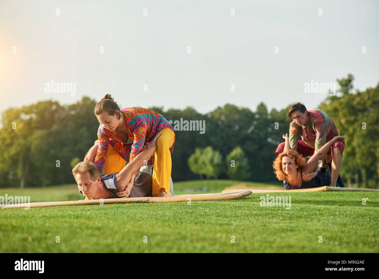 Yoga pose lying on stomach. Group thai massage on the lawn Stock Yoga pose lying on stomach. Group thai massage on the lawn Stock