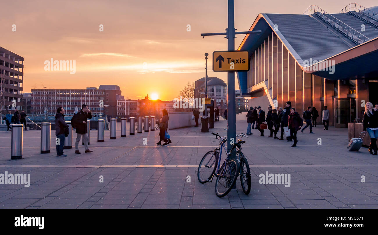 Reading, UK. 25th March 2018. UK Weather: A beautiful orange sunset as the sun sets in Reading on the first evening following the clocks moving forward to signify the start of British Summer Time. A line of bollards protects people outside Reading Railway Station which is the building on the right. Credit: Matthew Ashmore/Alamy Live News Stock Photo