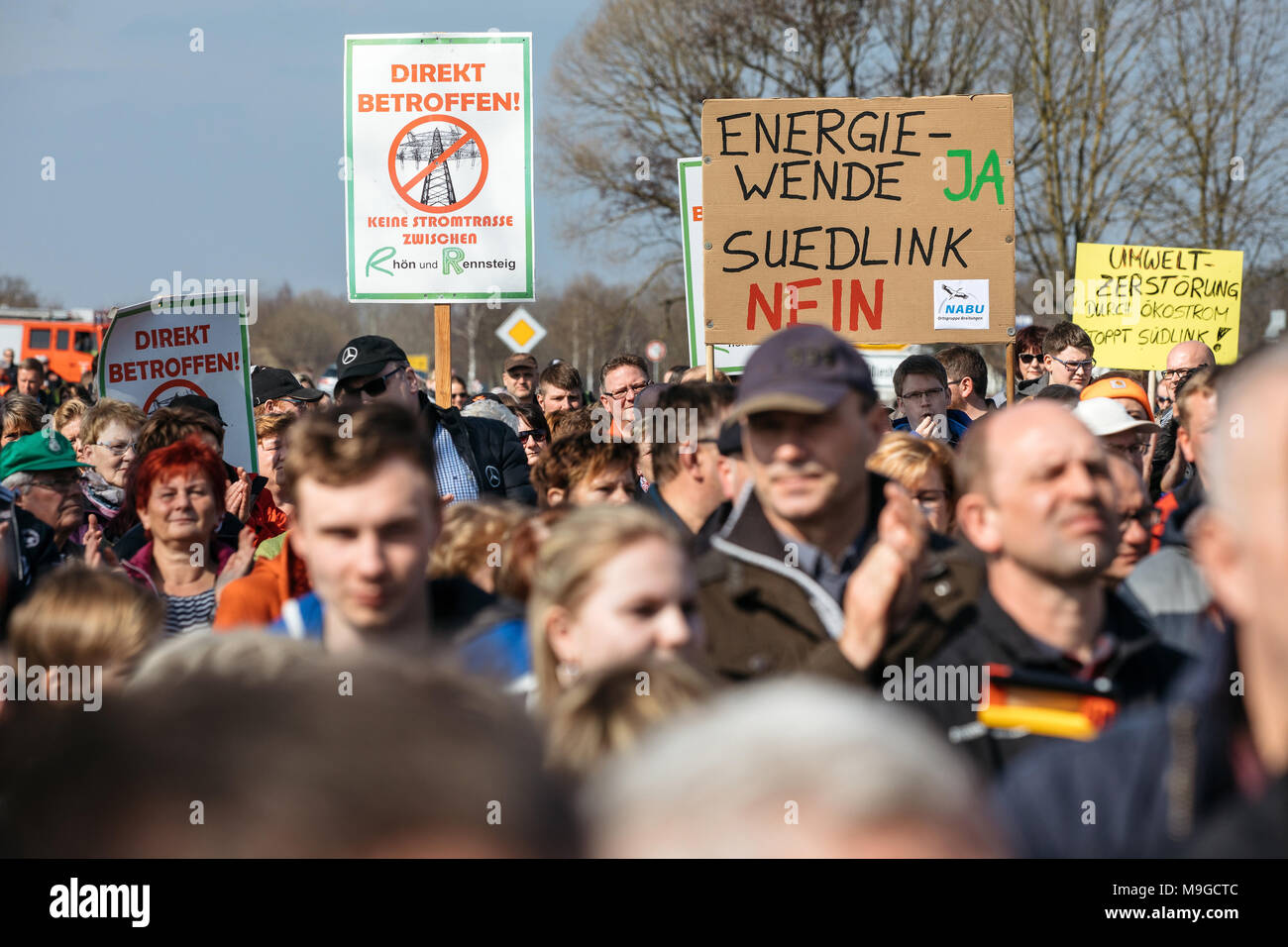 26 March 2018, Germany, Fambach: Numerous people holding up protest signs at the demonstration 'Keine Stromtrasse zwischen Rhön und Rennsteig' (lit. no power lines between Rhoen and Rennsteig). The demonstration is addressing the planned south link likes from network operator Tennet. Photo: Arifoto Ug/Michael Reichel/dpa Stock Photo