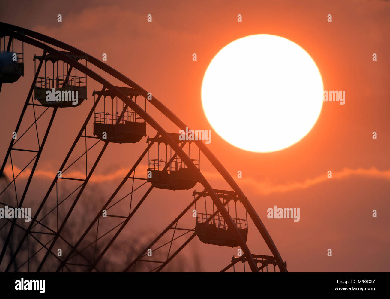 25 March 2018, Germany, Berlin: The sun setting behind the big wheel of the former theme park Plaenterwald. Photo: Soeren Stache/dpa Stock Photo