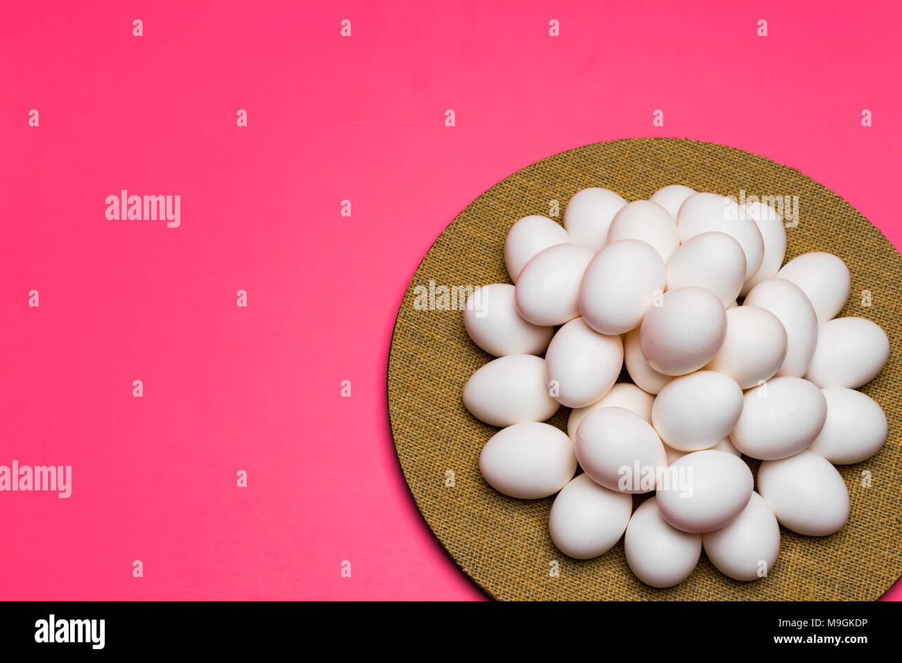 2 dozen uncolored Easter Eggs with a pink pastel background with negative space on a plate ready to be colored. Stock Photo