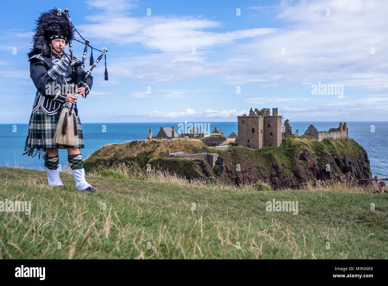 Traditional scottish bagpiper in full dress code at Dunnottar Castle in Stonehaven Stock Photo