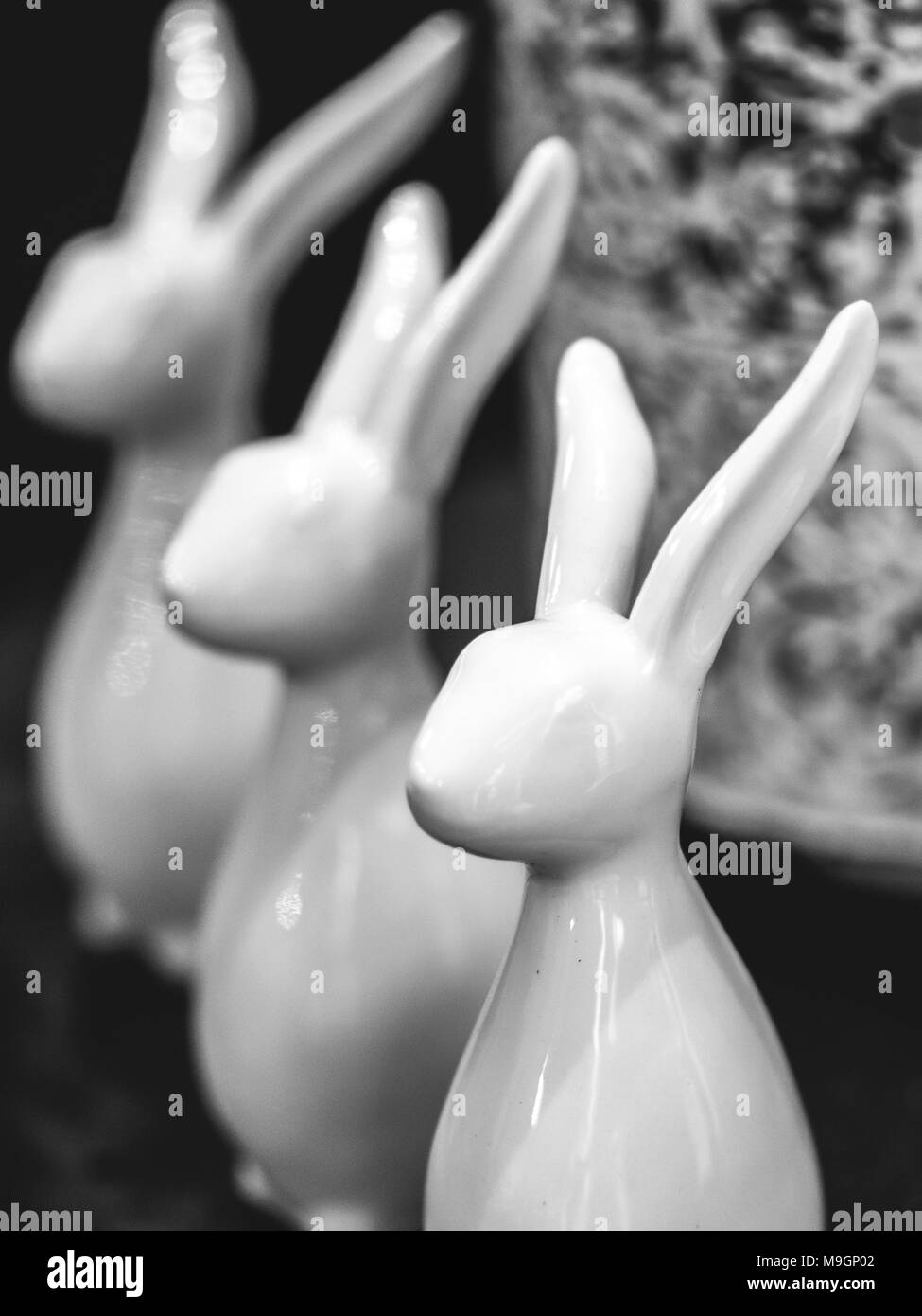 three porcelain hare on a small table, 3 pieces, in black and white Stock Photo