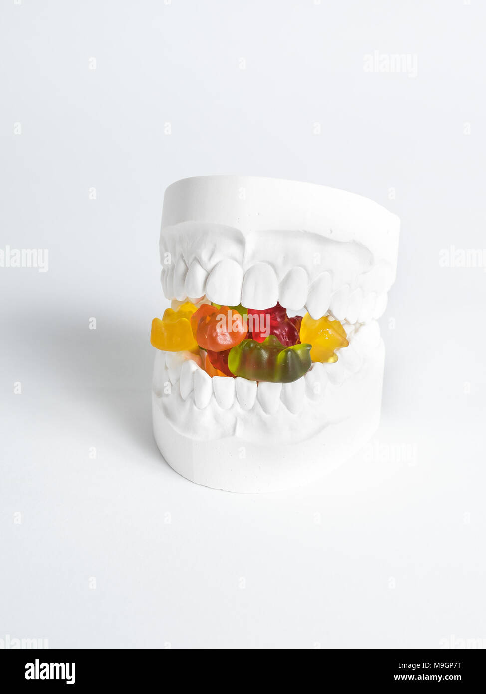 The plaster bit has gummy bears between its teeth against a white background Stock Photo