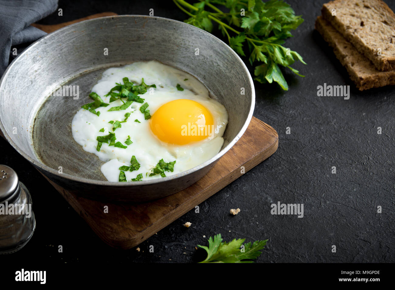 Fried Egg on Frying Pan for Breakfast. Fried egg with bread and parsley
