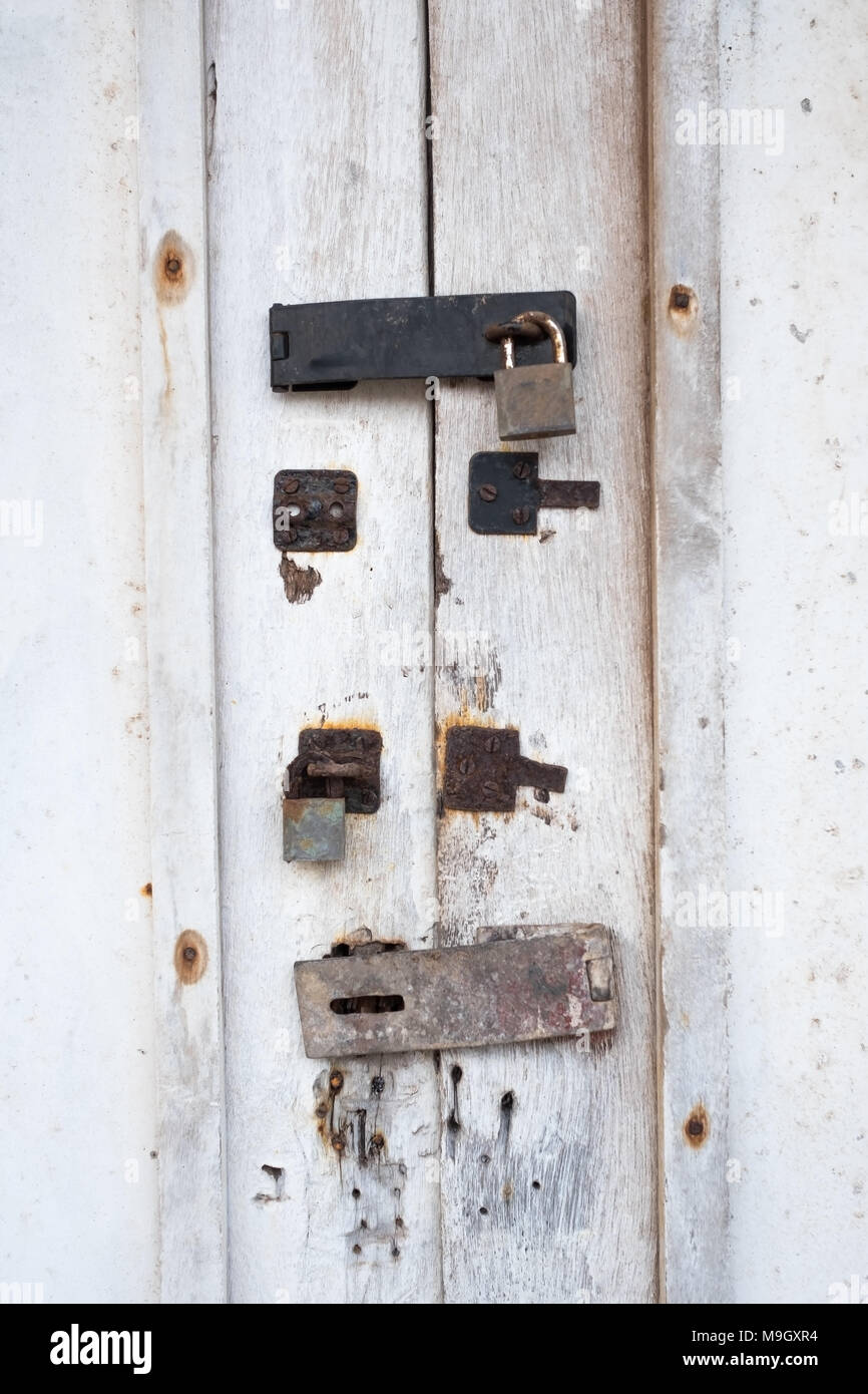 White door with an old lock with traces of previous locks on it Stock Photo