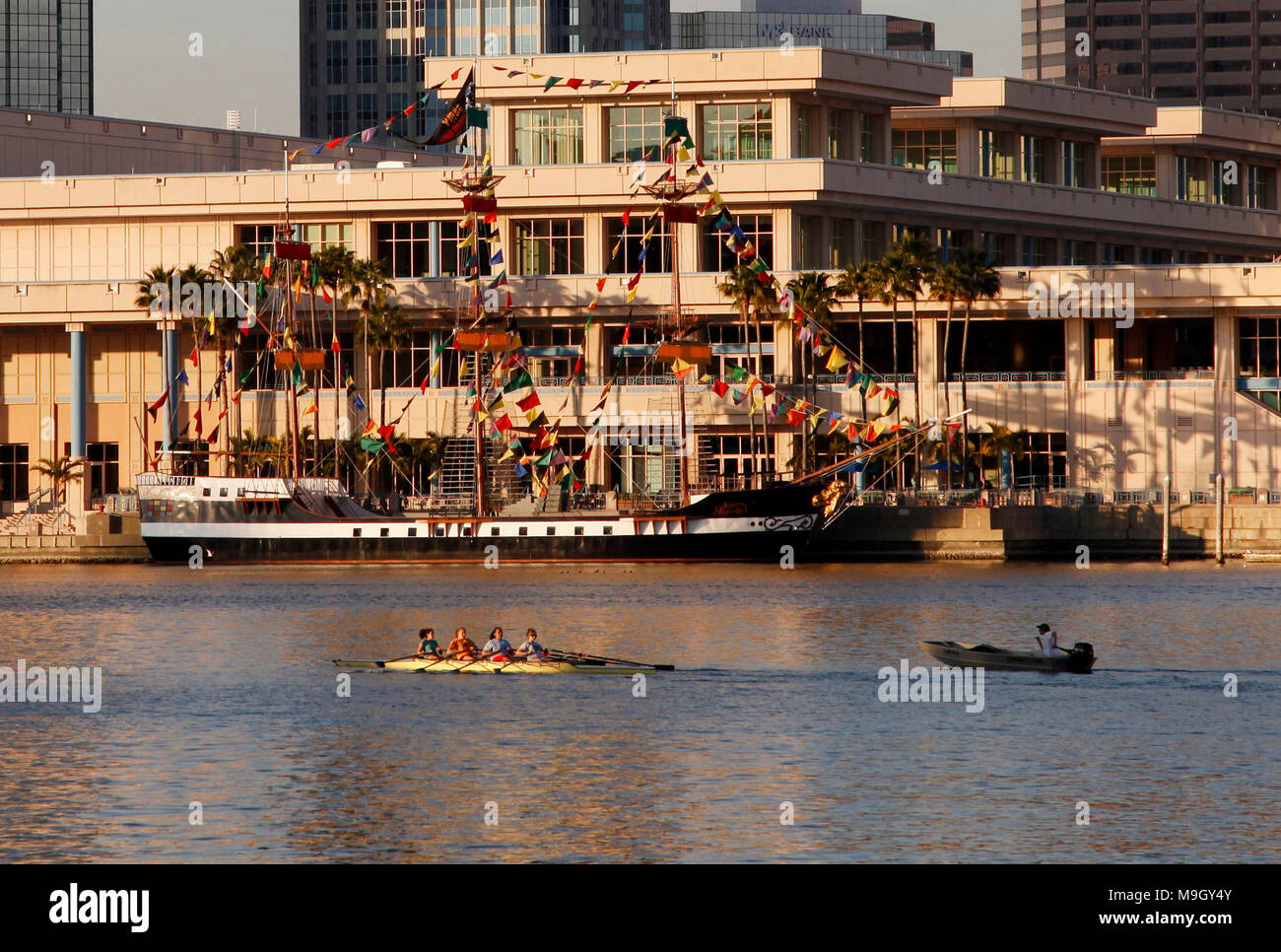 A team of rowers paddles in a crew boat along a pirate ship moored in Downtown Tampa, Florida. Stock Photo