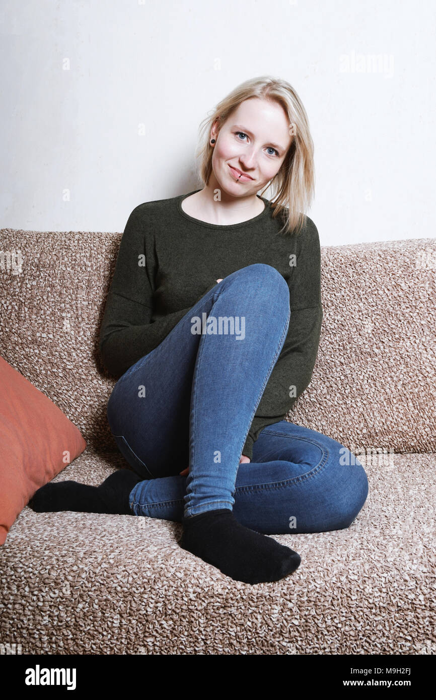 young woman sitting on sofa at home Stock Photo - Alamy