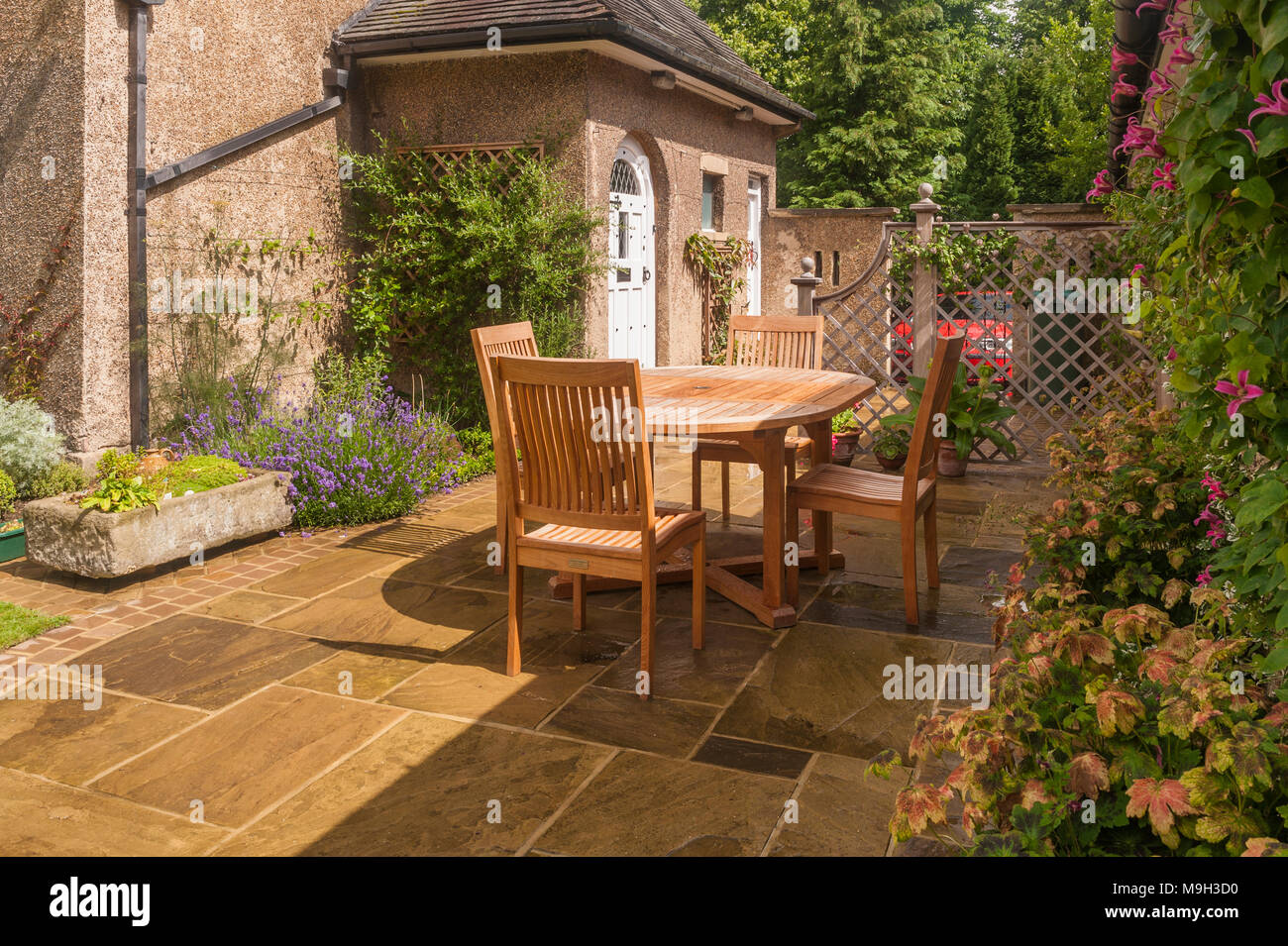 Designed Landscaped Garden With Paved Patio Trellis Screen Table Chairs By Rear Door Of Arts Crafts Style House West Yorkshire England Uk Stock Photo Alamy