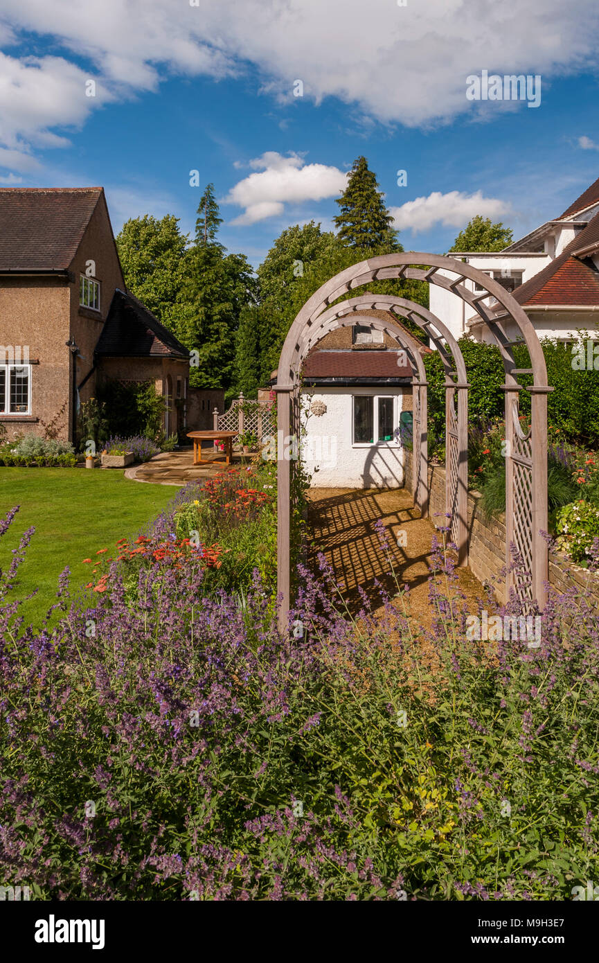 Summer view of sunlit tunnel arbour & colourful herbaceous border - beautiful, designed, landscaped, traditional garden, West Yorkshire, England, UK. Stock Photo