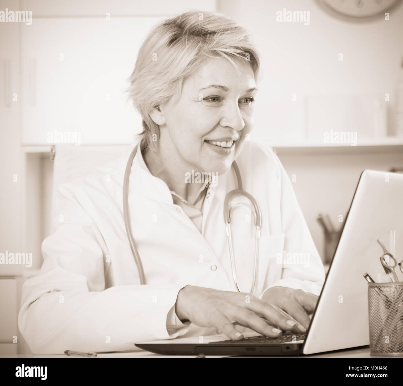 Doctor in white medical dressing gown waiting for patients at office