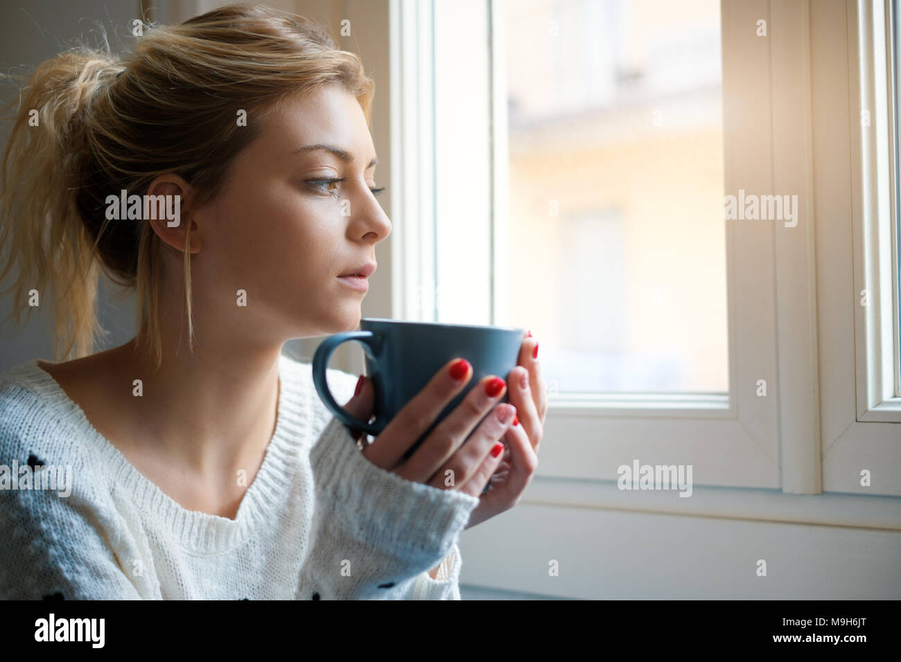Girl feeling in a bad mood and drinking hot drink Stock Photo