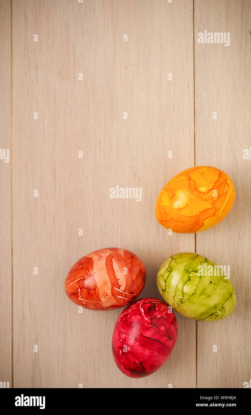 Four colored Easter eggs on a bright wooden taxture Stock Photo