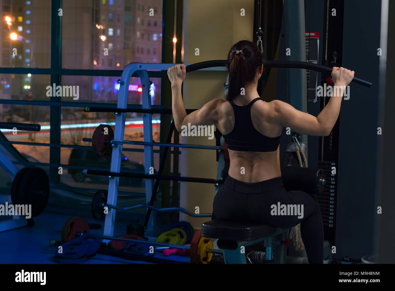 Woman on cable pull down machine at gym Stock Photo
