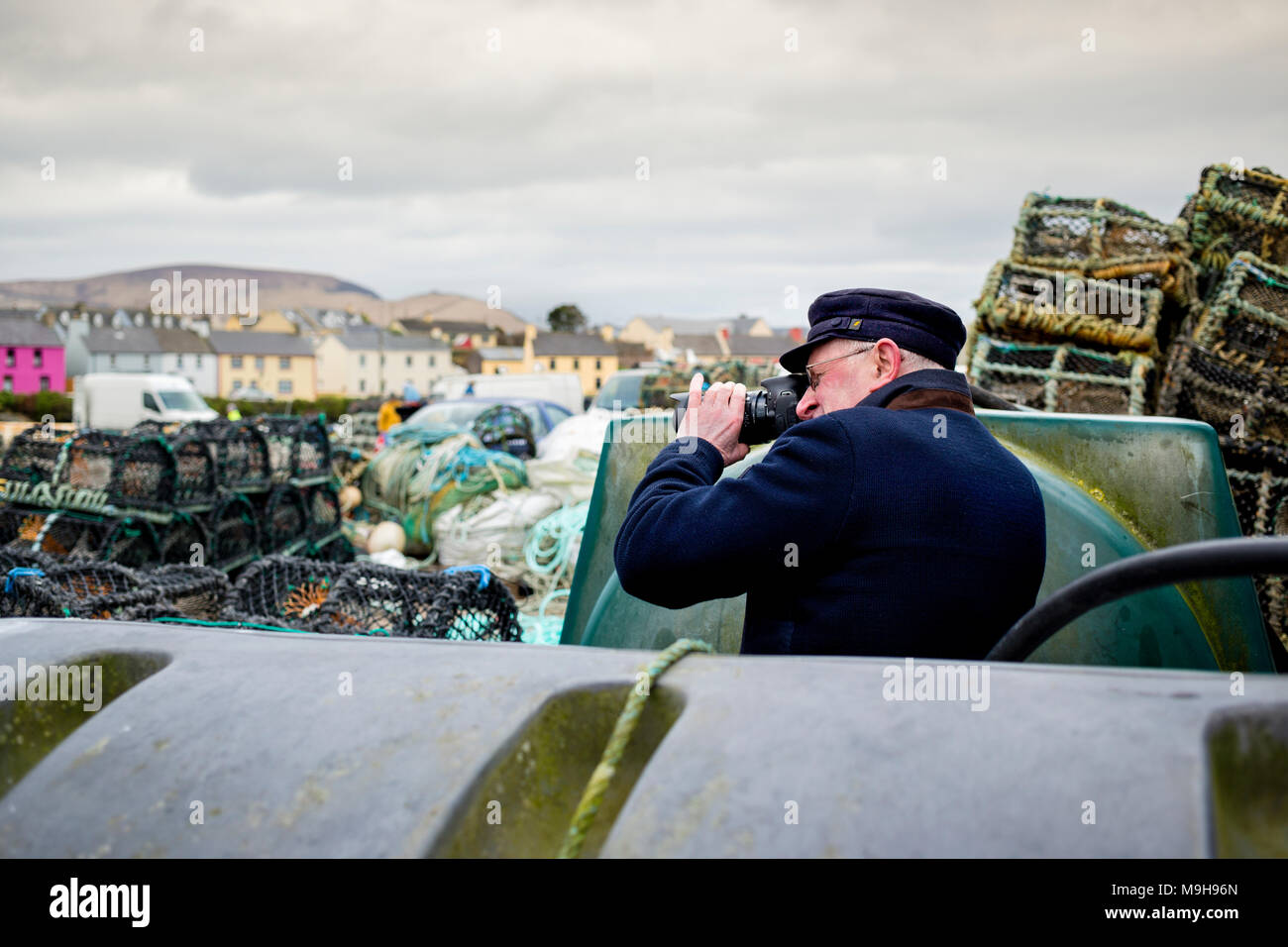 Older man photographing at a fishing village in County Kerry, Ireland Stock Photo